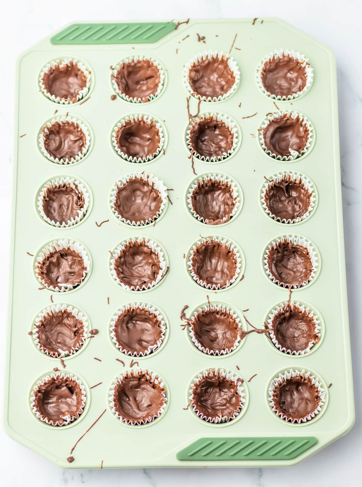 Coating muffin liners with melted chocolate.