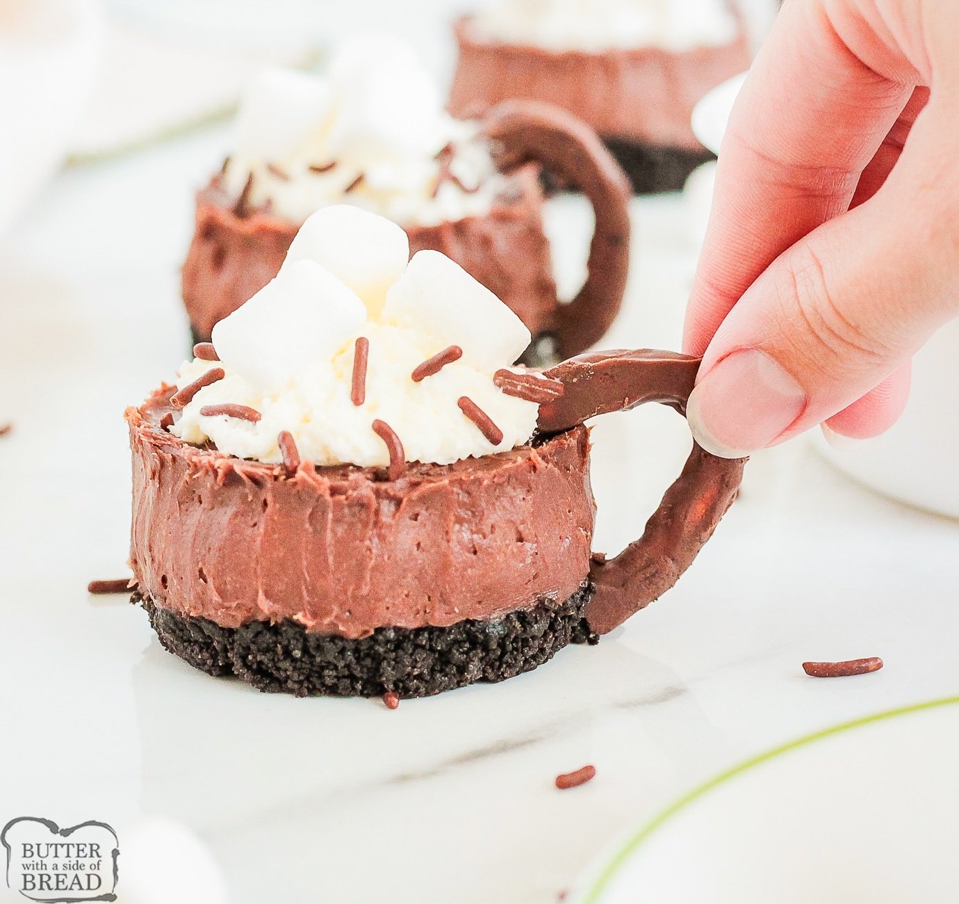holding a hot chocolate cheesecake by its chocolate pretzel handle