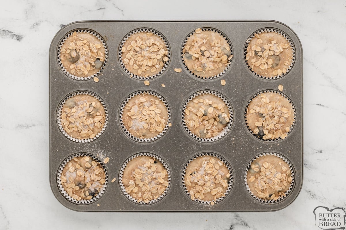 Sprinkling oat topping on muffins before baking. 