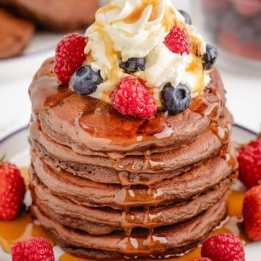 chocolate pancakes with berries, syrup and whipped cream
