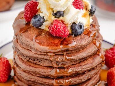 chocolate pancakes with berries, syrup and whipped cream