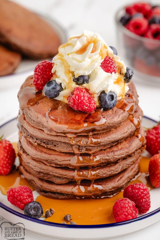 chocolate pancakes with berries, syrup and whipped cream