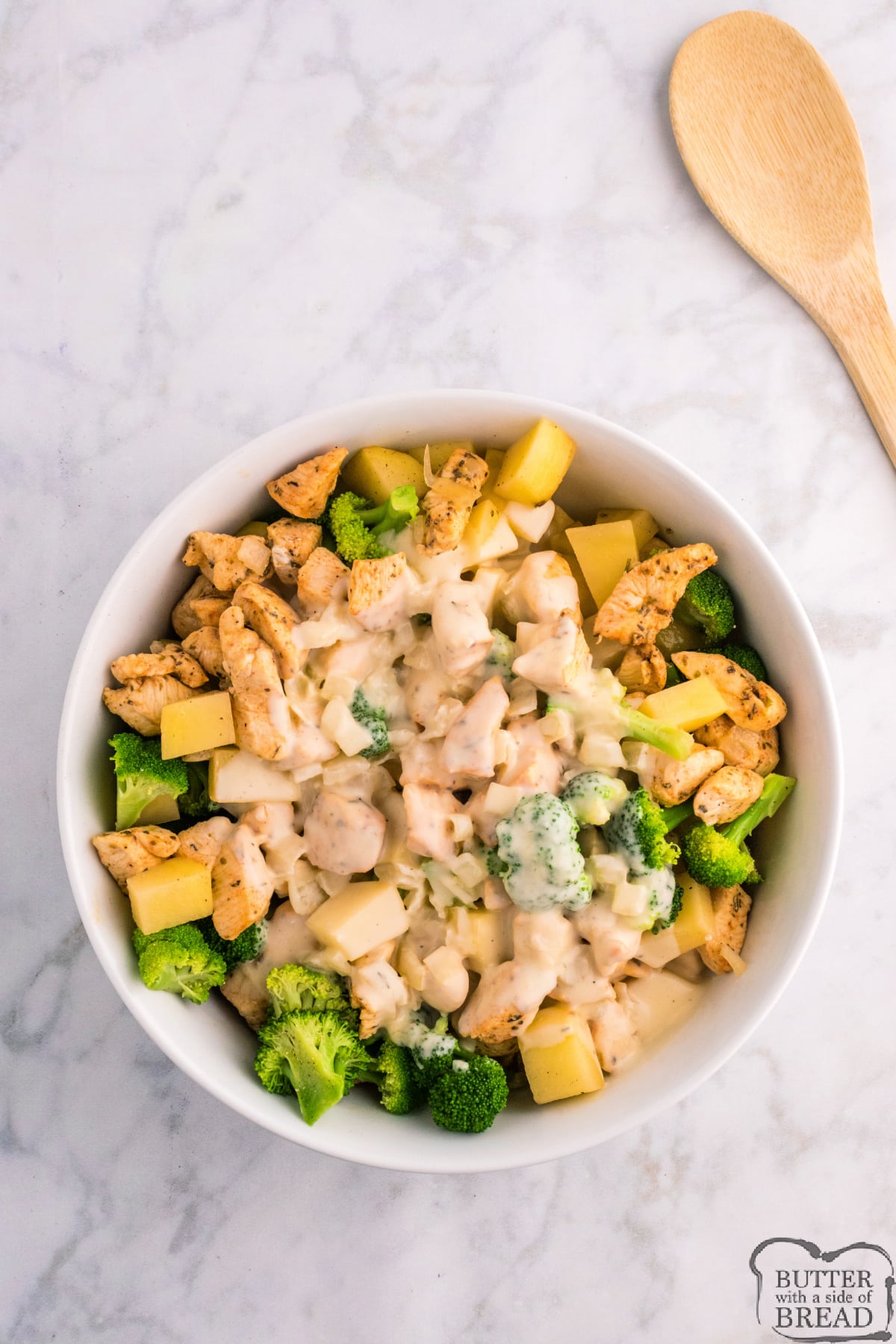 Mixing sauce with potatoes, broccoli, and chicken. 