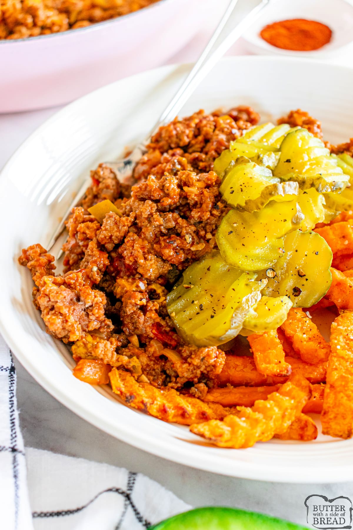 Sloppy joe bowl with pickles and sweet potato fries. 