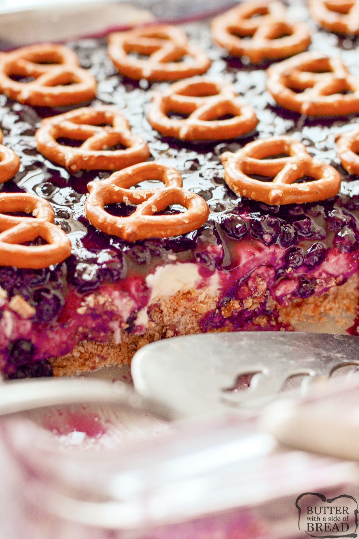 Dessert with pretzel crust, cream layer, and blueberry filling.