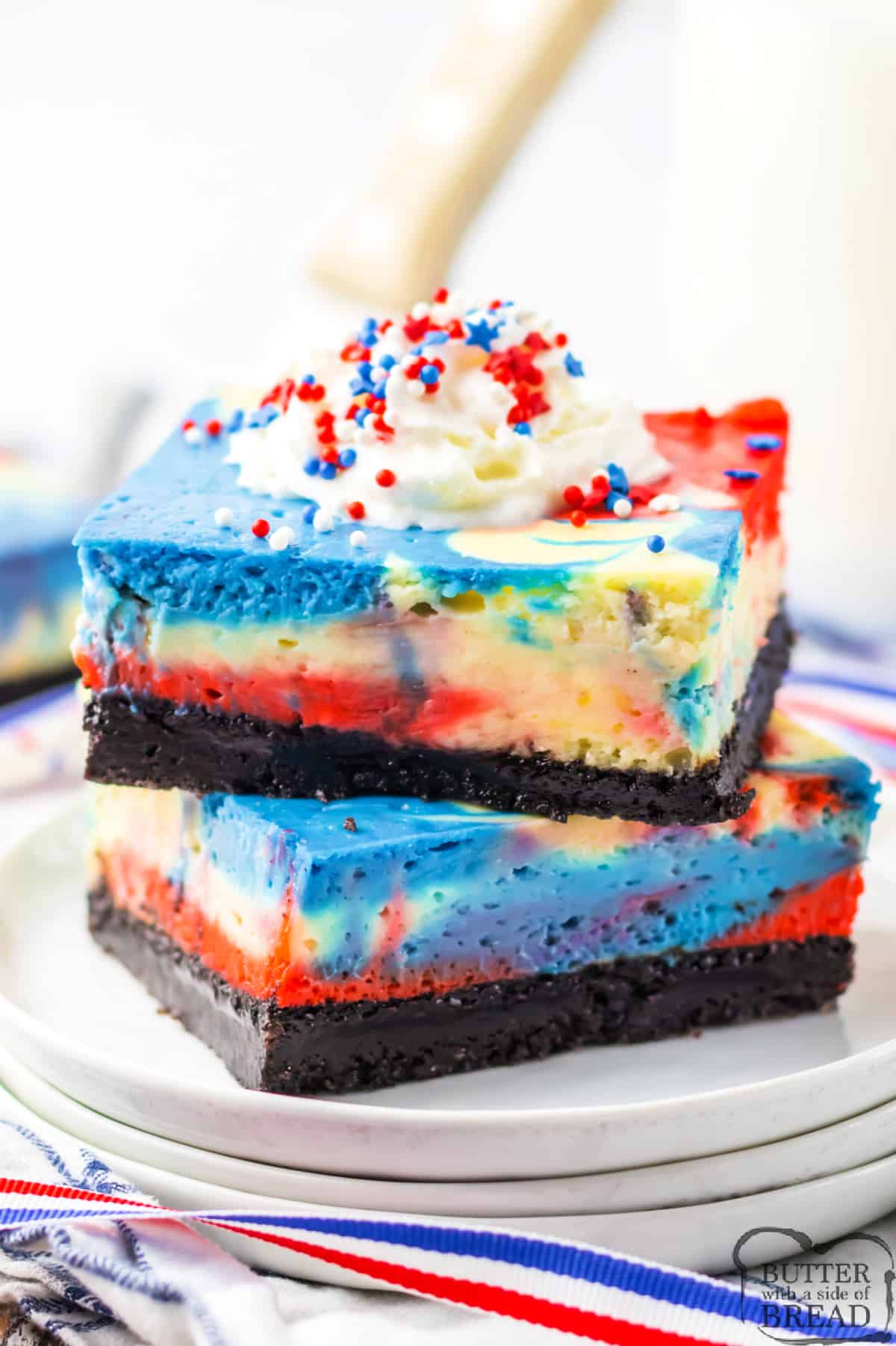 Red, White & Blue Cheesecake Bars are perfect for the 4th of July, Memorial Day, or any other patriotic occasion! Add a simple cheesecake filling to an Oreo crust to make this delicious dessert recipe!