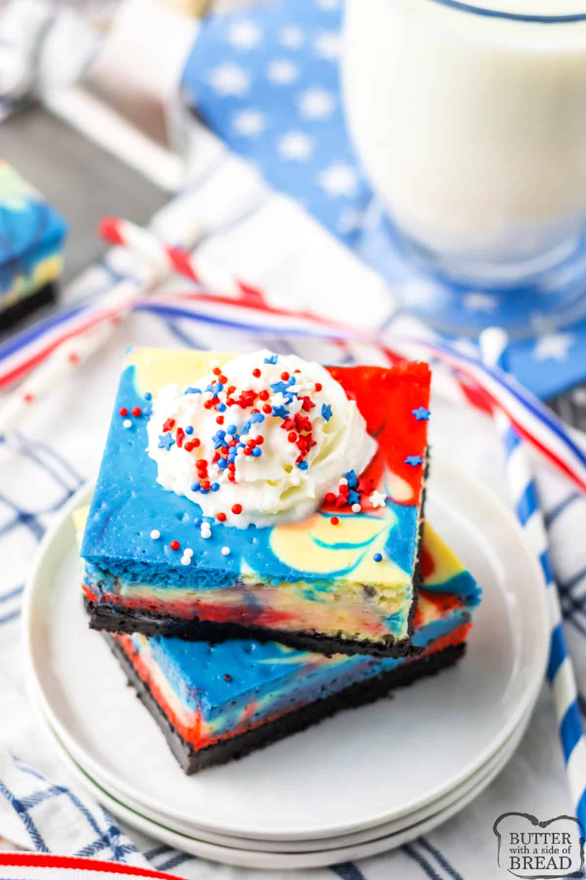 Red, white and blue cheesecake bars with whipped cream and sprinkles.