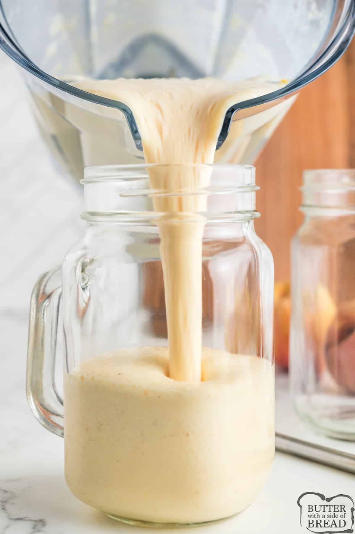 Pouring peach milkshake recipe into a glass mug.