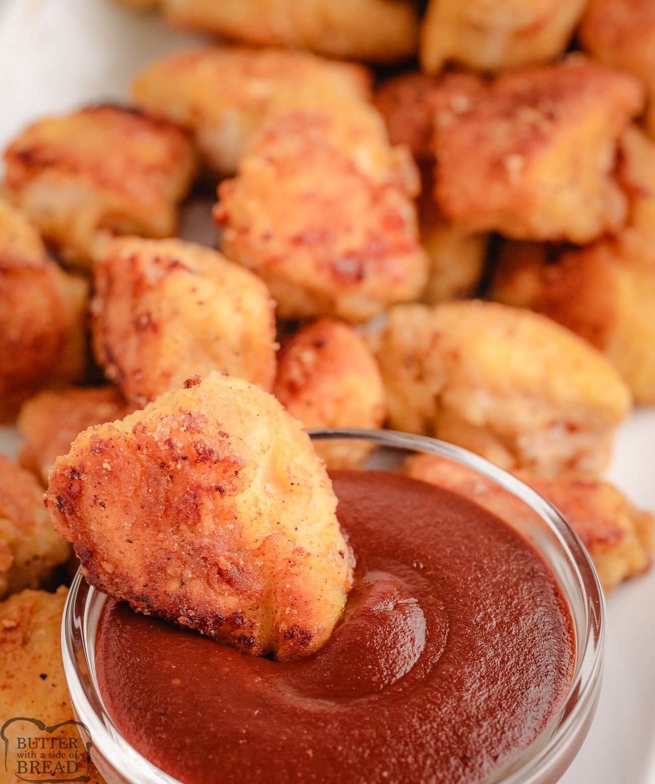 dipping a homemade chicken nugget in BBQ sauce