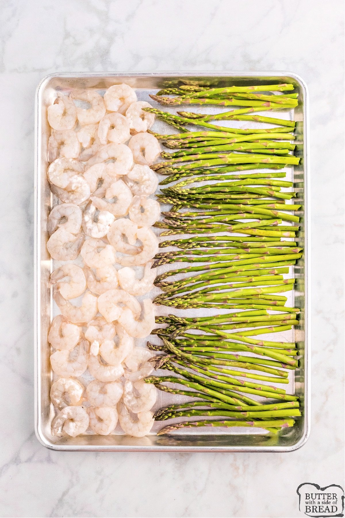 Placing shrimp and asparagus on baking sheet. 