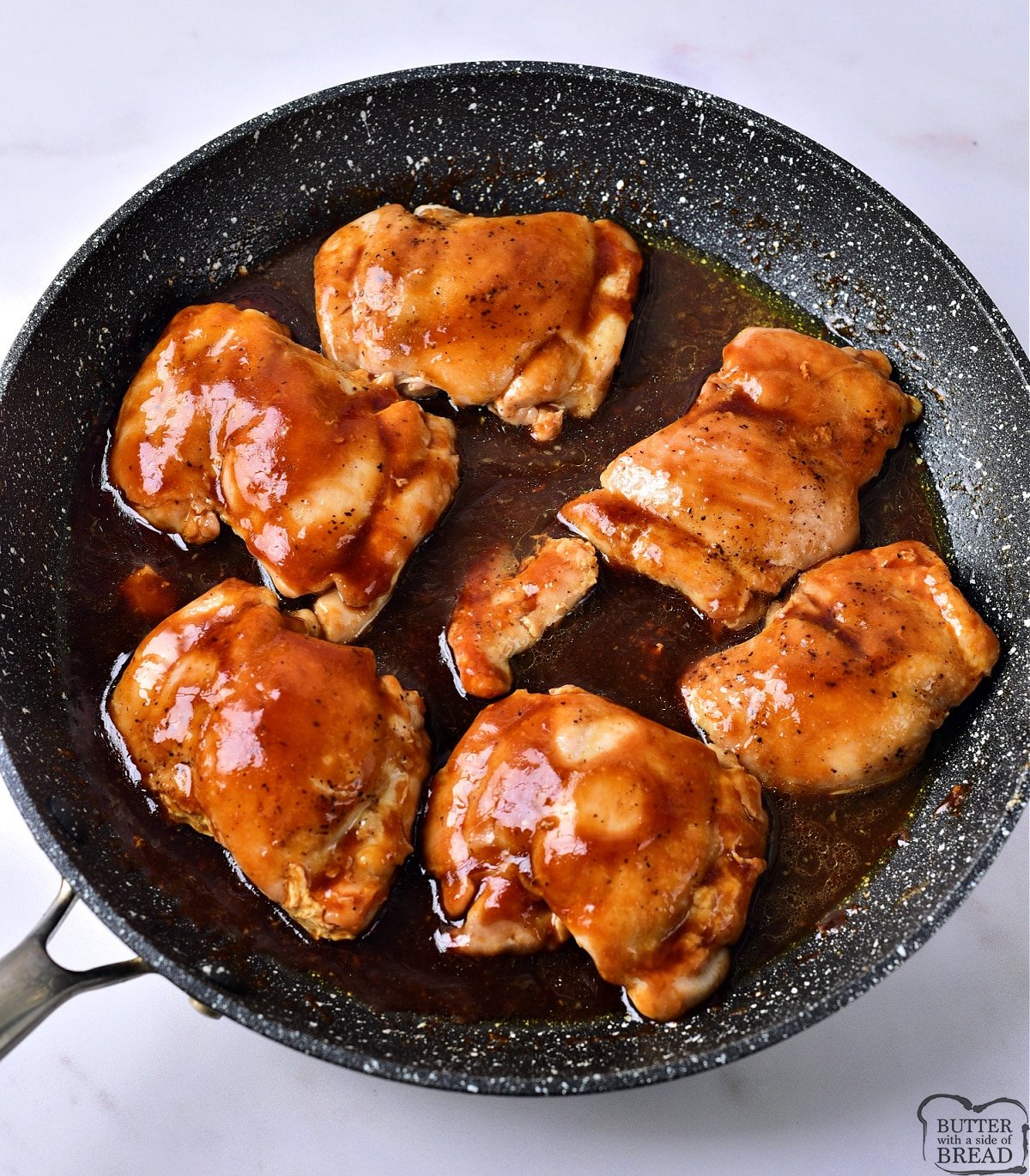 Chicken thighs with sauce in a skillet. 