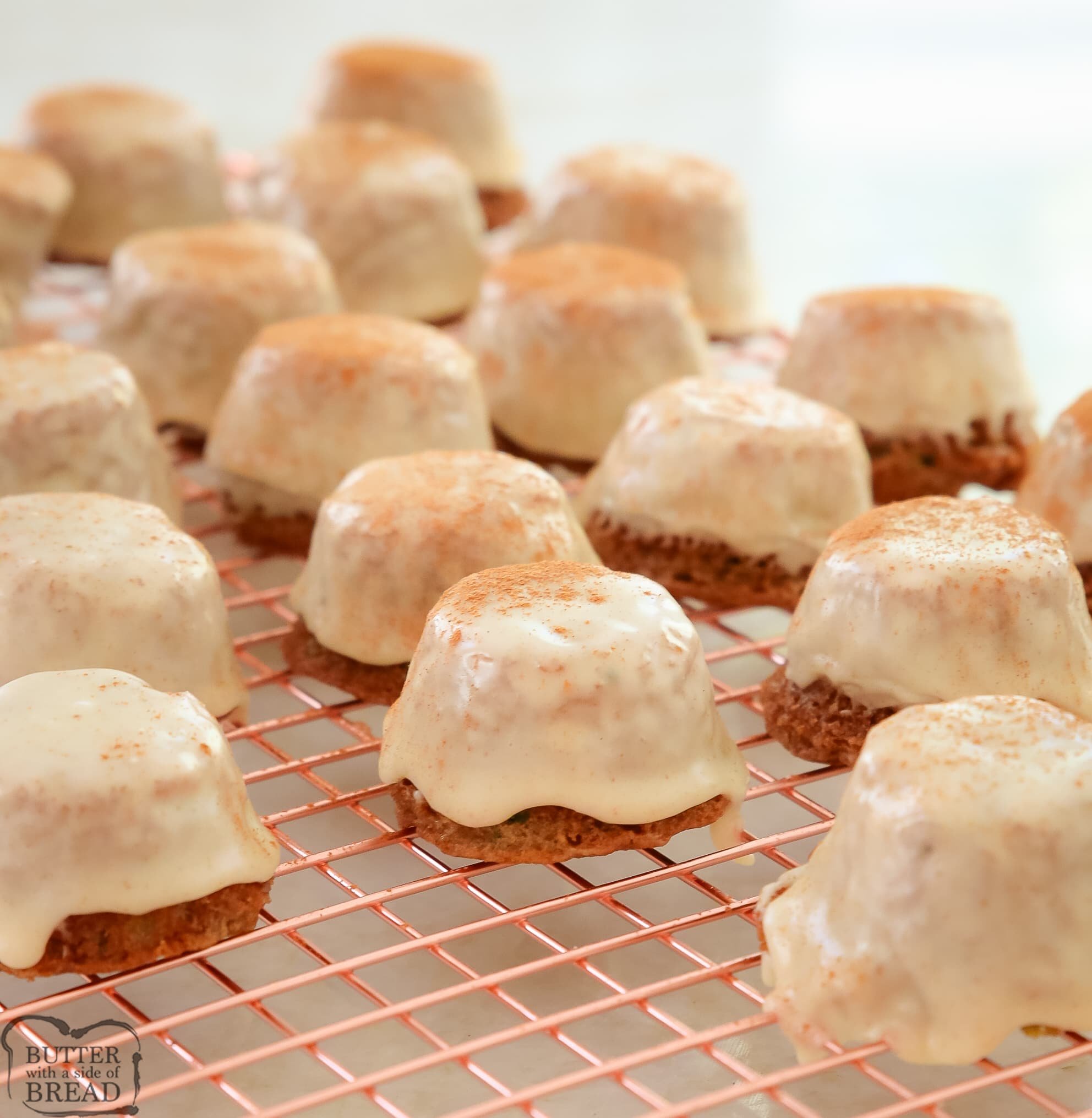 zucchini bread bites with brown butter icing cooling on a rose gold cooling rack