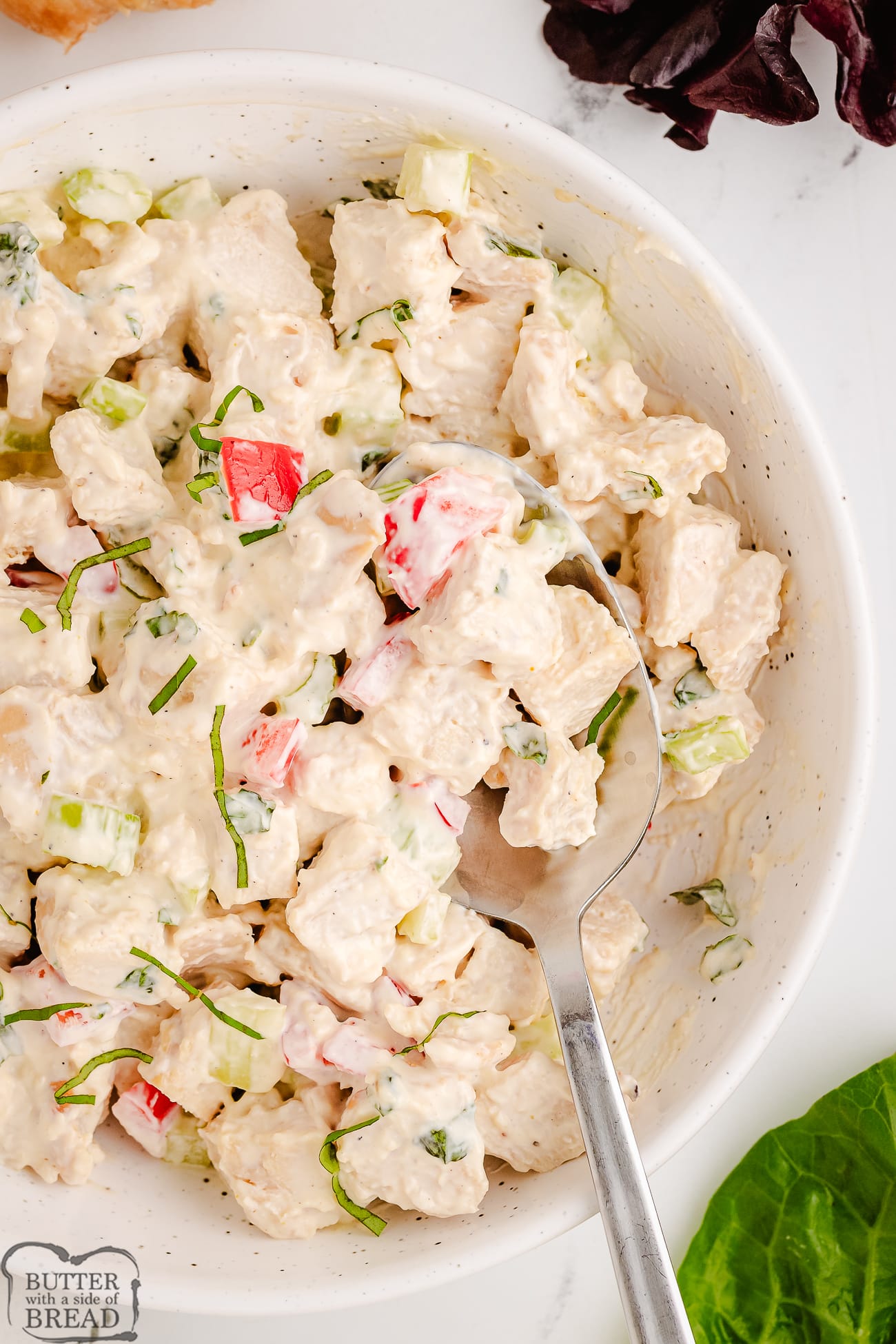 scooping out basil chicken salad from a white bowl