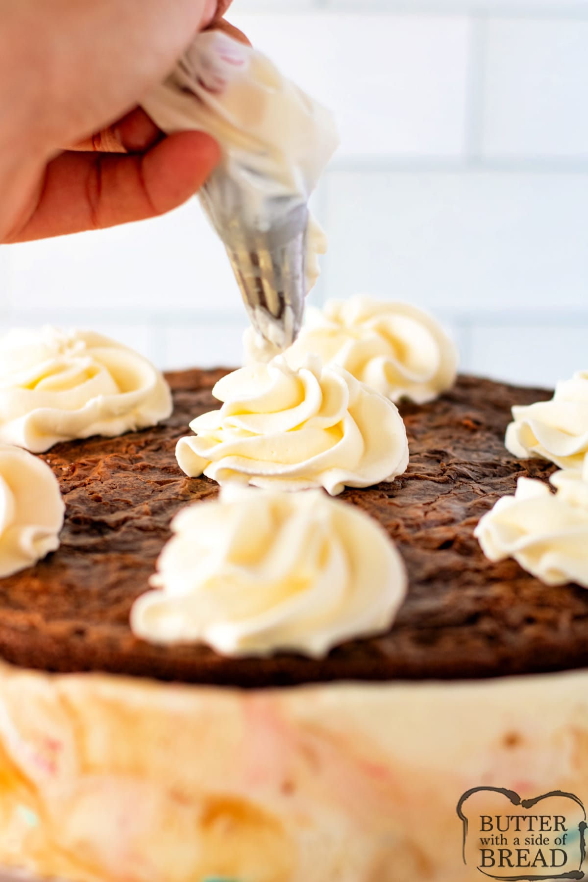 Adding whipped cream to the top of the ice cream cake. 