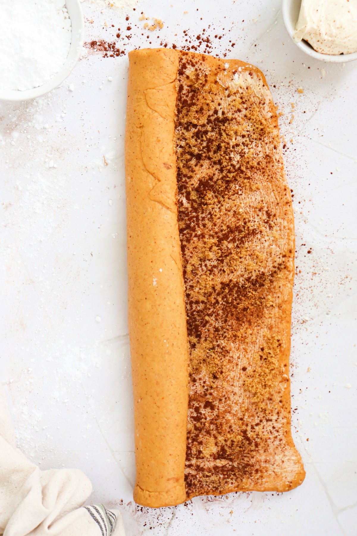 Rolling up pumpkin cinnamon roll dough. 