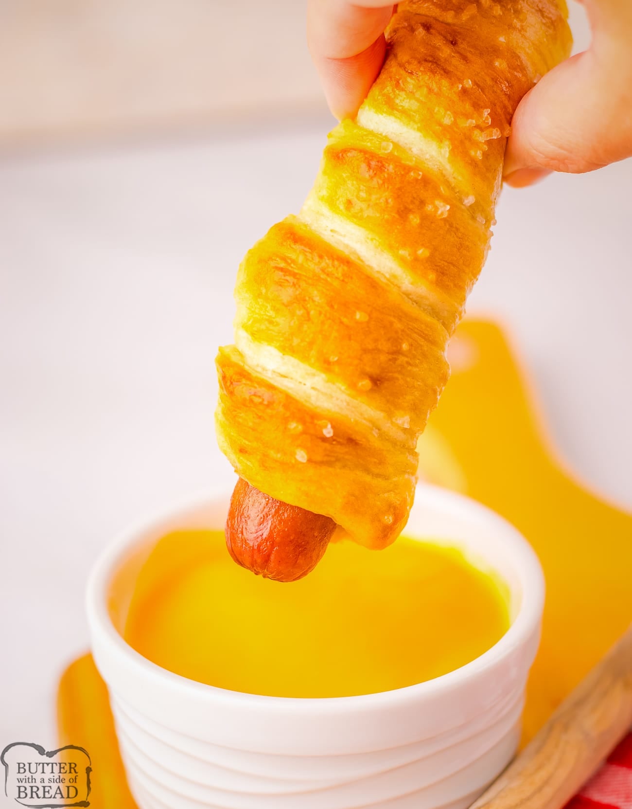 dipping a pretzel hot dog in cheese sauce
