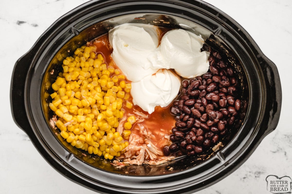 Add beans, corn, and sour cream to the shredded chicken.
