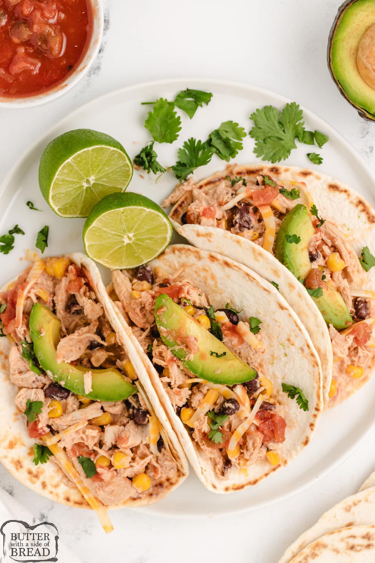 Chicken tacos with salsa, avocados, cheese, corn, and beans.