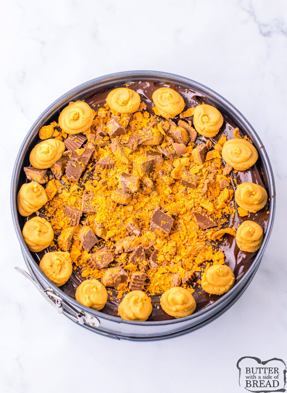 Copycat Cheesecake Factory Adam's Peanut Butter Cup Cheesecake is made with an Oreo crust, crushed Butterfingers, chopped peanut butter cups, and hot fudge. This decadent cheesecake is topped off with a peanut butter cream cheese frosting.