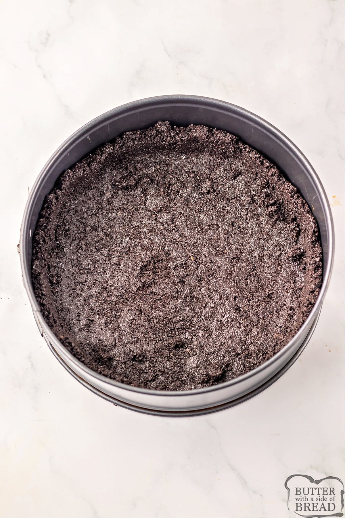 Pressing Oreo crust into a springform pan. 