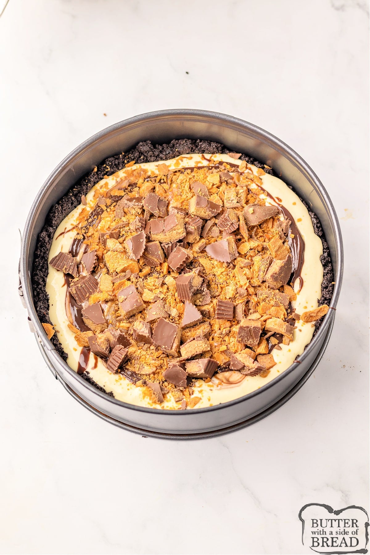 Add crushed peanut butter cups and Butterfingers to the middle of the cheesecake. 