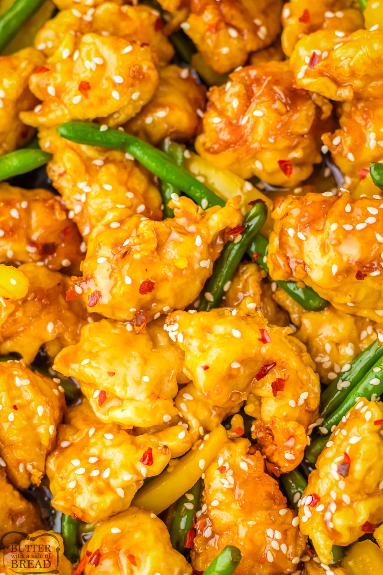 honey sesame chicken in a pan with green beans