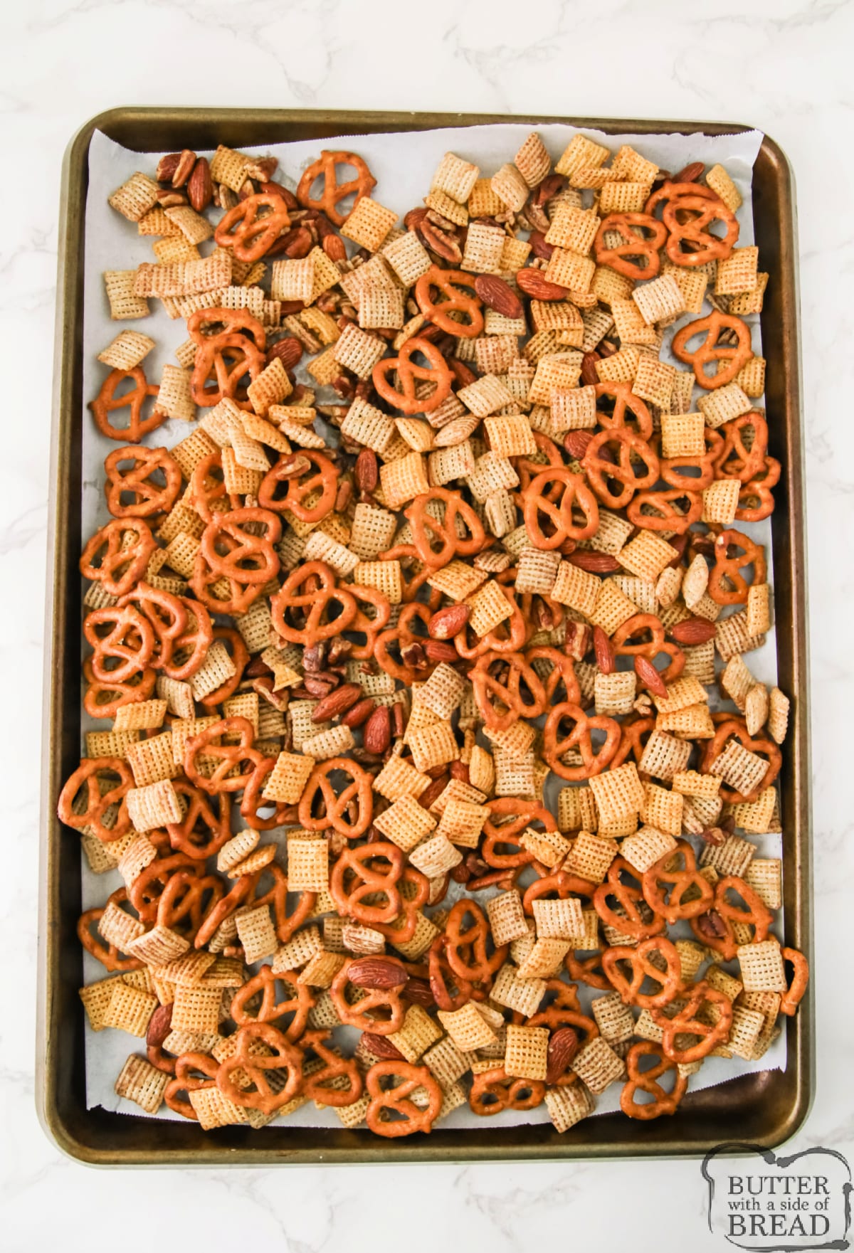 Chex snack mix spread out on baking sheet.