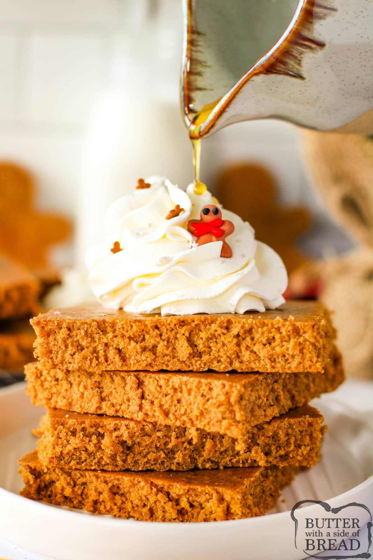 Stack of gingerbread pancakes with whipped cream and maple syrup.