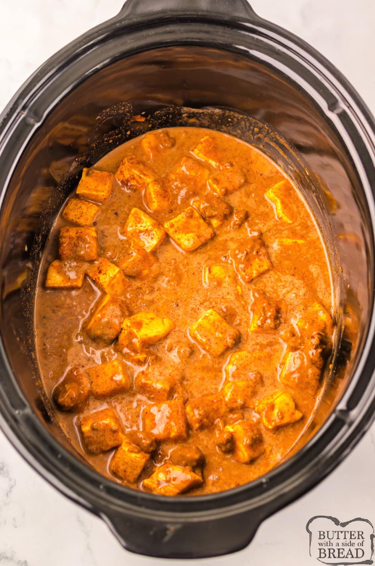 Adding ingredients to the slow cooker to make queso dip.