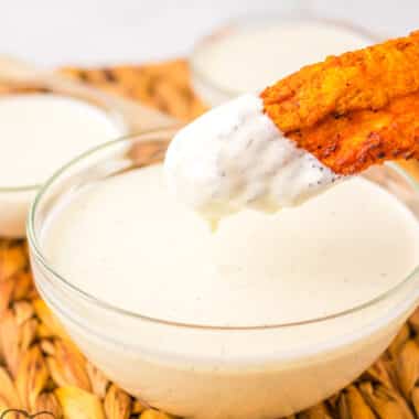 wingstop Ranch in a bowl with a chicken wing dipped in it