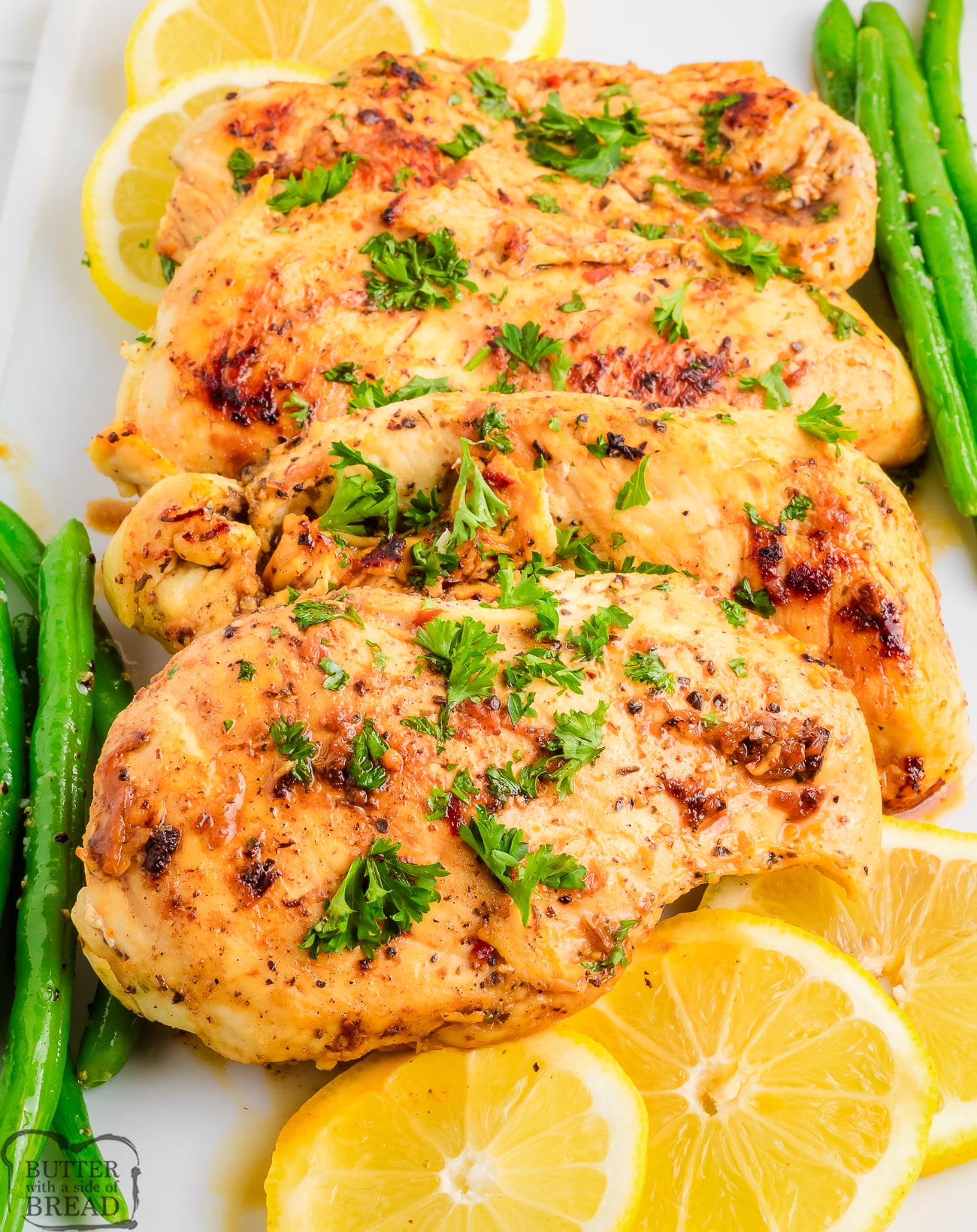 Lemon Garlic Chicken on a platter with vegetables and lemon slices