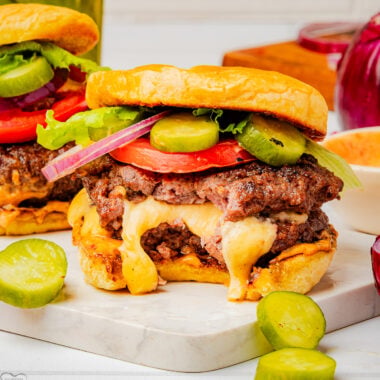 homemade Juicy Lucy cheese stuffed burger with a bite taken out and cheese oozing from the beef