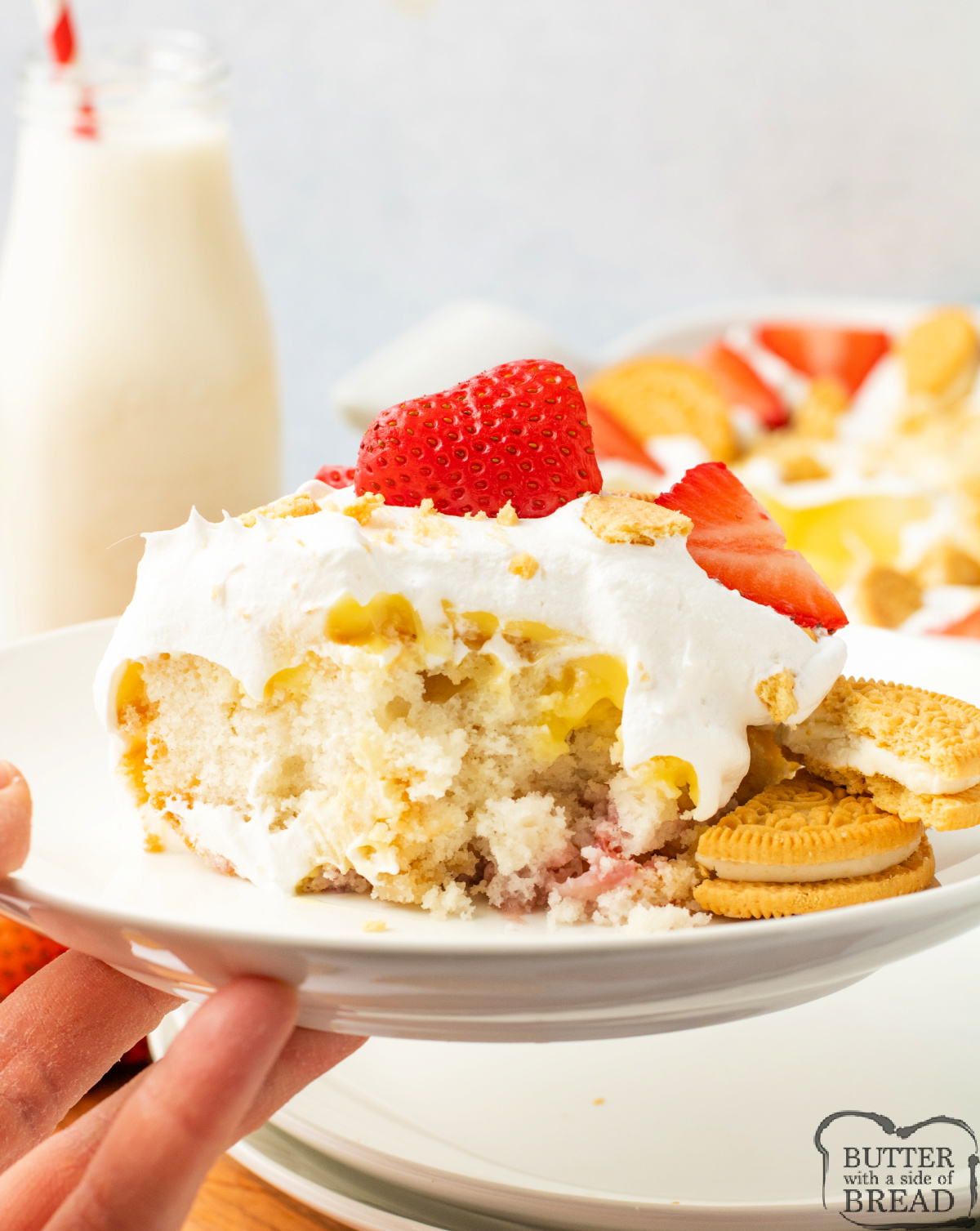 Poke cake made with vanilla pudding, fresh strawberries, and Golden Oreos.