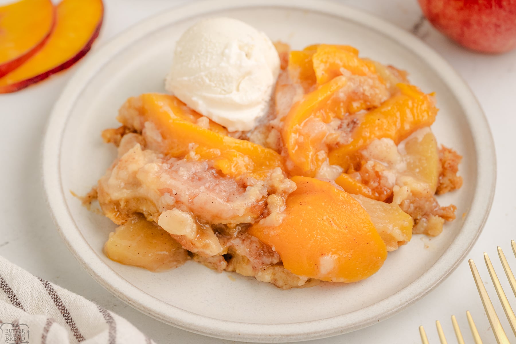 serving of apple and peach cobbler on a cream plate with vanilla ice cream
