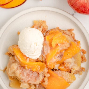 Apple and Peach Cobbler on a white plate with vanilla ice cream
