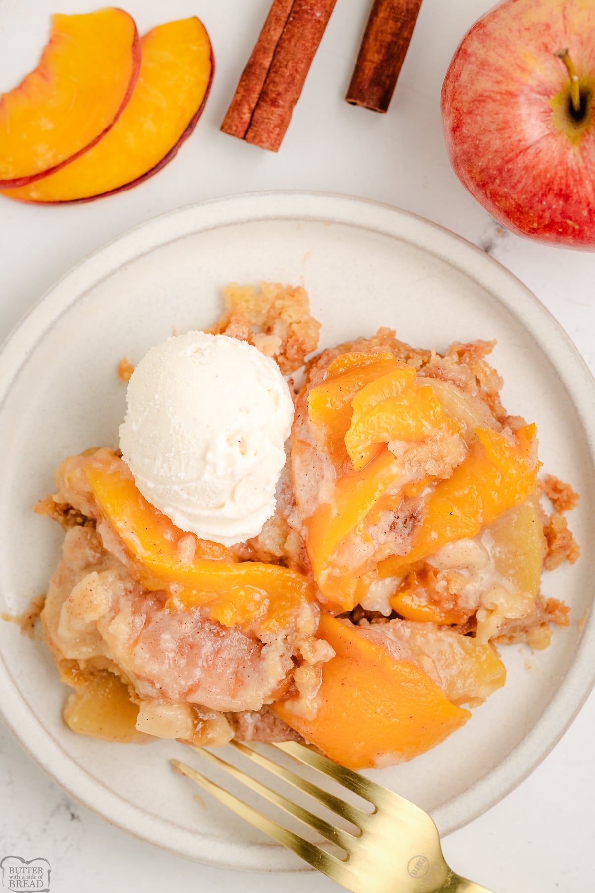 Apple and Peach Cobbler on a white plate with vanilla ice cream