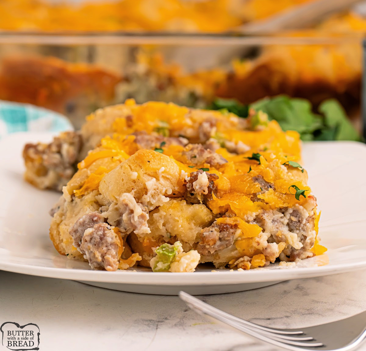 Serving of Biscuits and Gravy Casserole with fluffy biscuit pieces, sausage gravy, and gooey cheese on a plate.