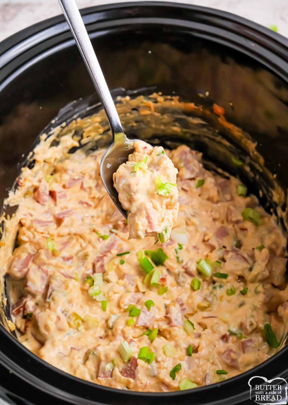 Slow cooker sausage dip topped with melted cheese and green onions.