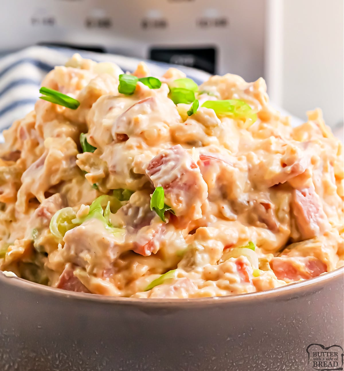 Slow cooker sausage dip with melted cheddar and Monterey Jack, garnished with green onions and ready for dipping.