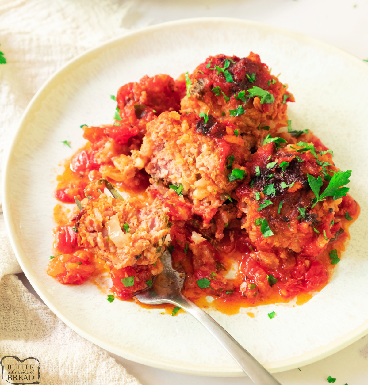 Serving of porcupine meatballs on a white plate with parsley garnish.