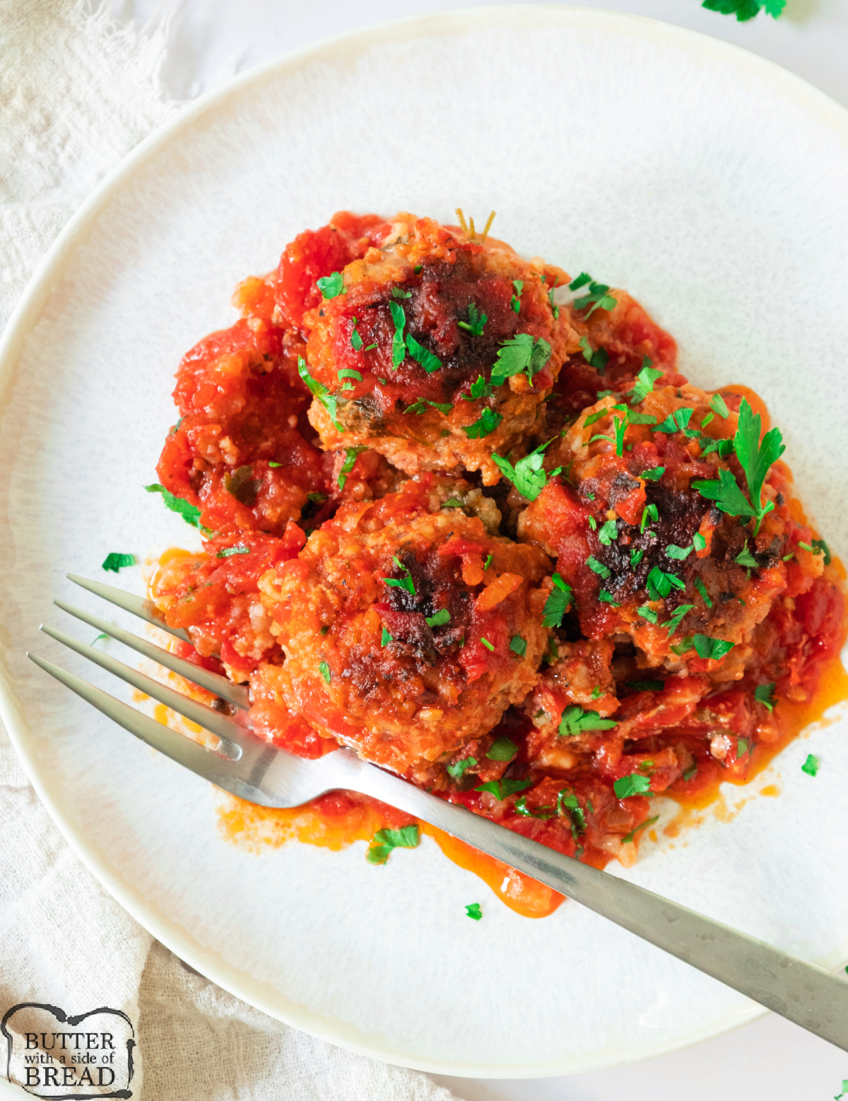 Plate of porcupine meatballs in tomato sauce, garnished with fresh parsley.