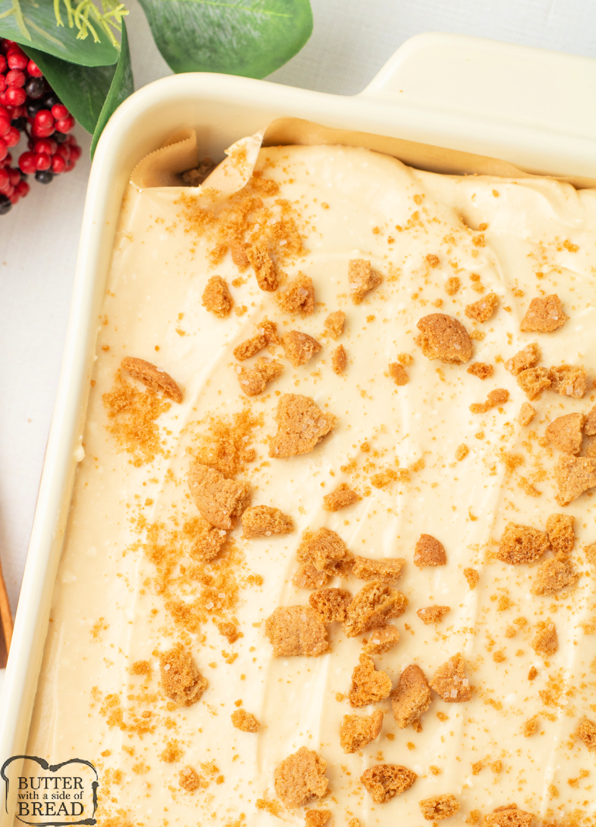Overhead view of Gingerbread Poke Cake in a 9x13 pan covered with creamy frosting, and cookie crumbles.
