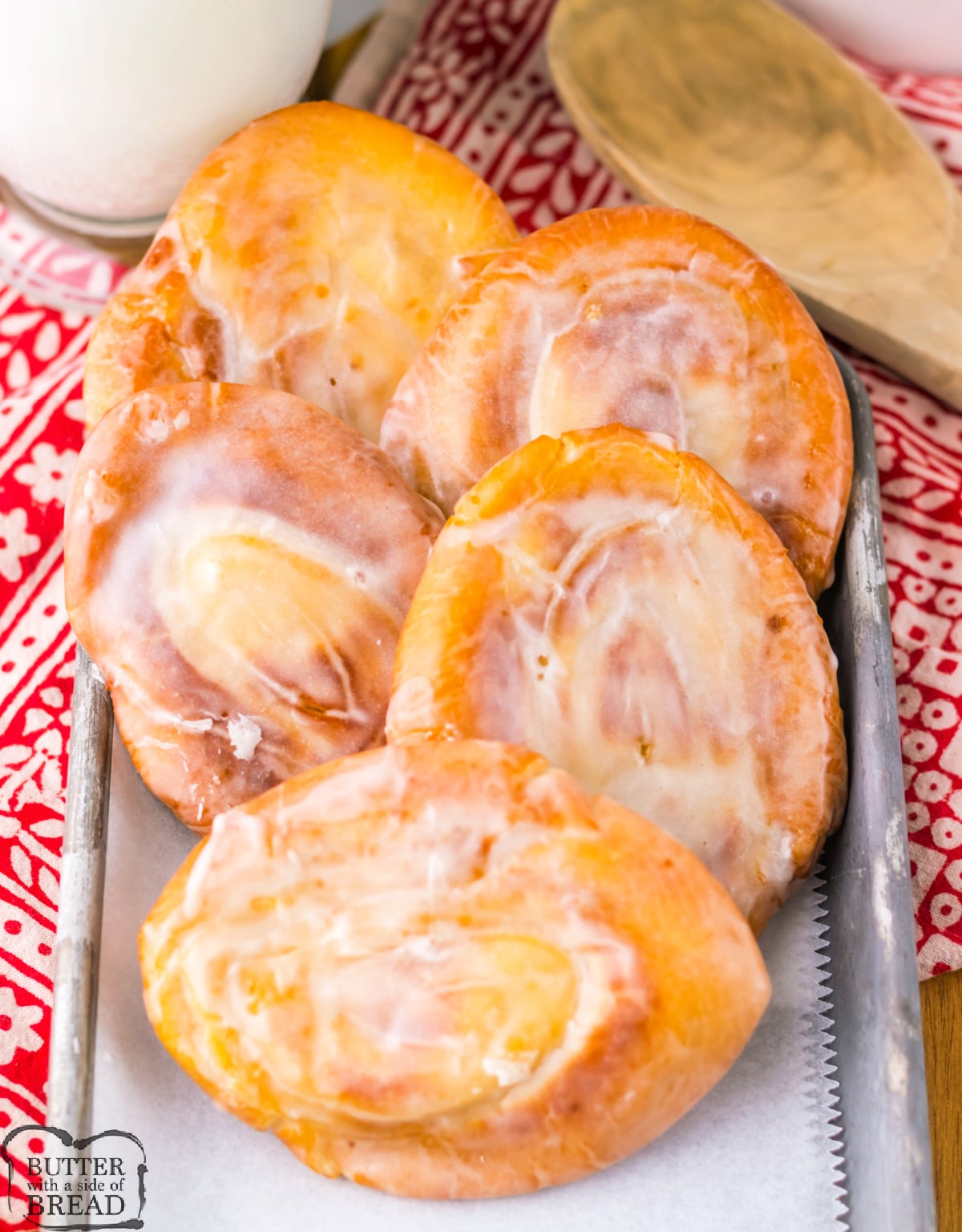 Freshly glazed honey buns stacked on a plate with glaze dripping down the sides.