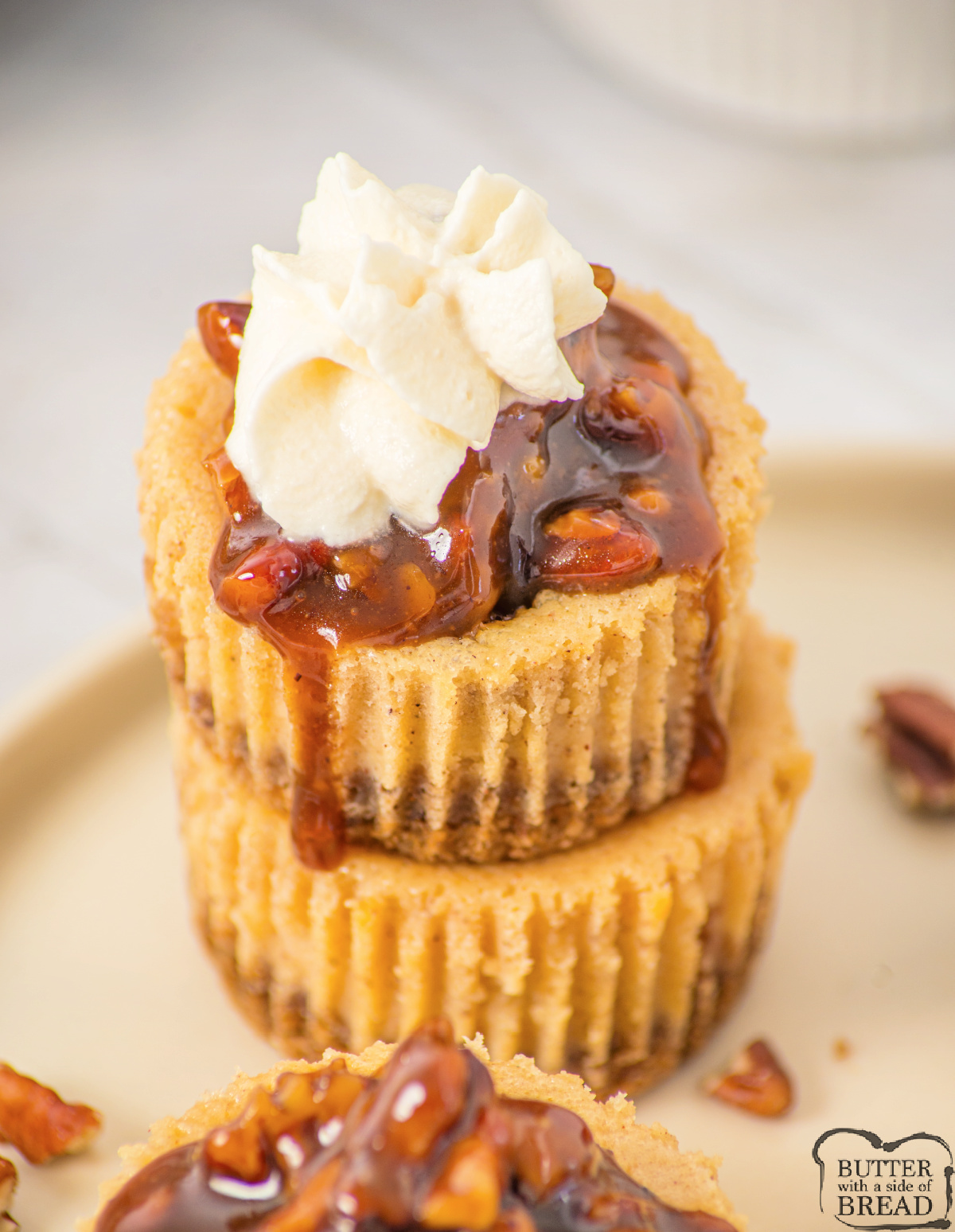 Mini pecan pie cheesecakes topped with caramel pecan sauce on a plate.