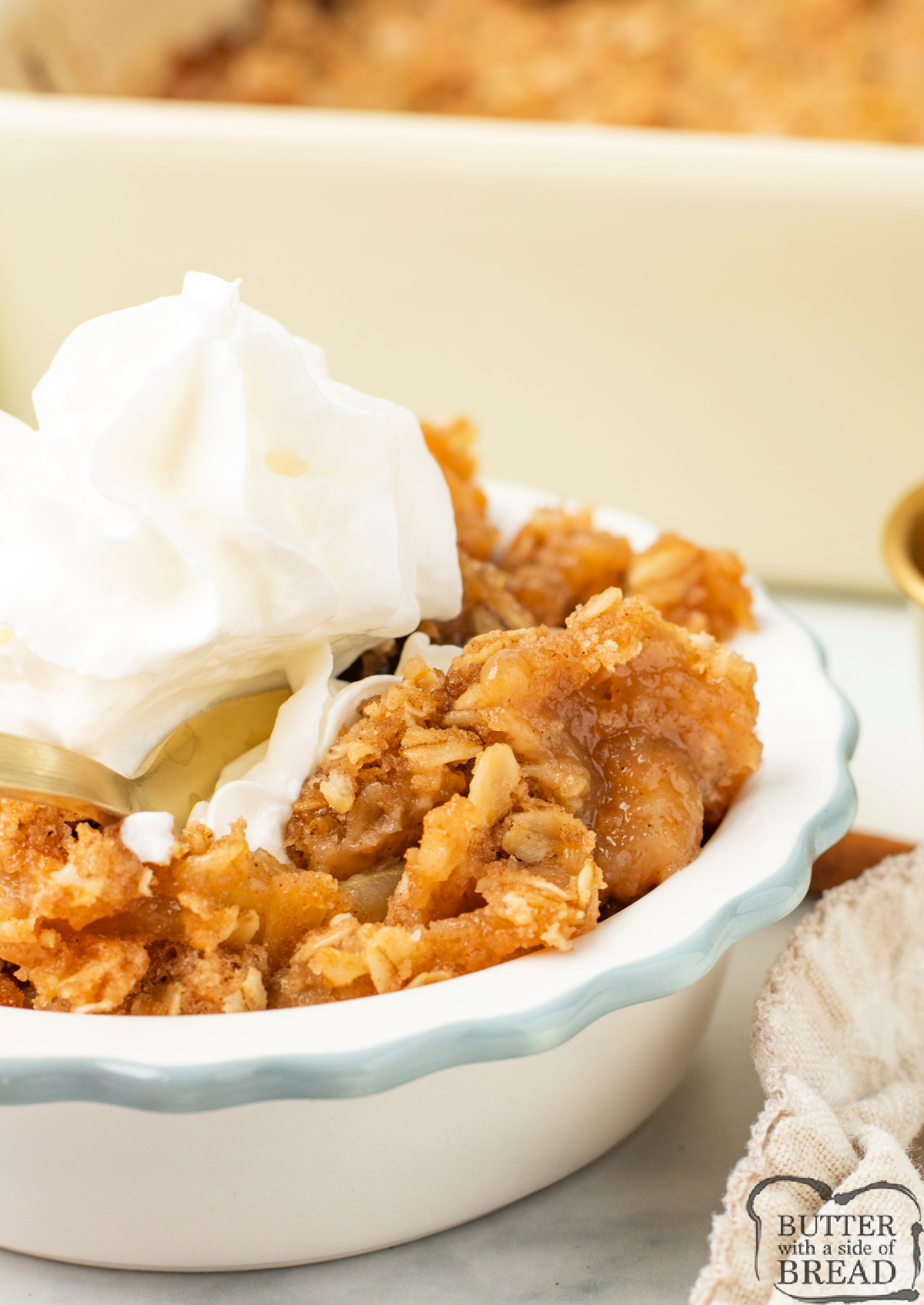 Scooped portion of applesauce crisp in a bowl with whipped cream.