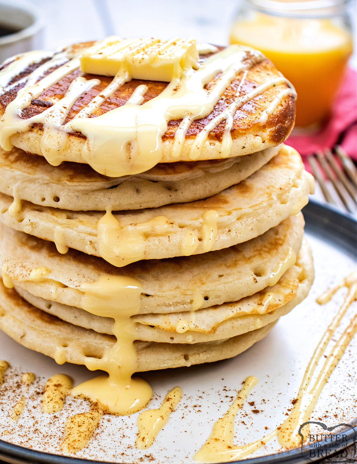 Eggnog pancakes stacked high with cinnamon, butter, and a creamy eggnog drizzle on a white plate.