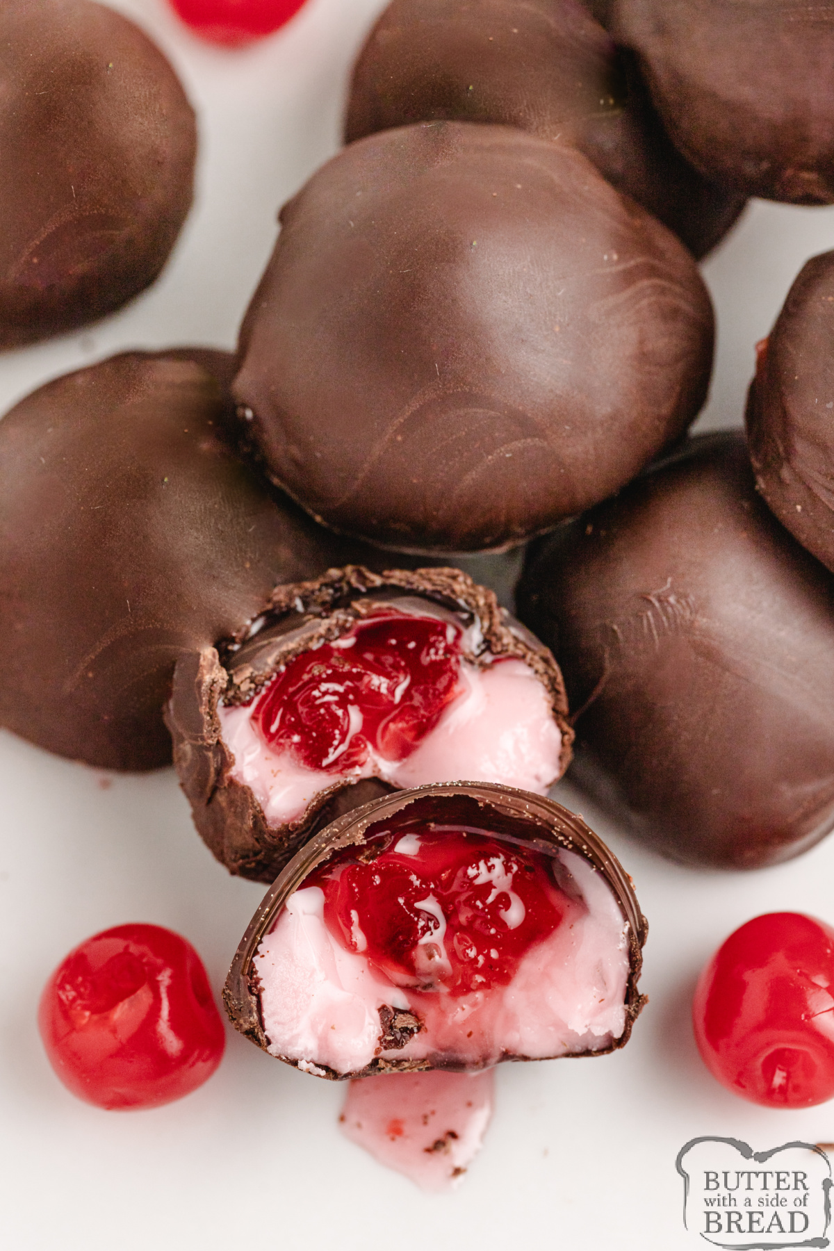 Chocolate-covered cherries displayed on a plate with a few cherries showing the soft fondant center.