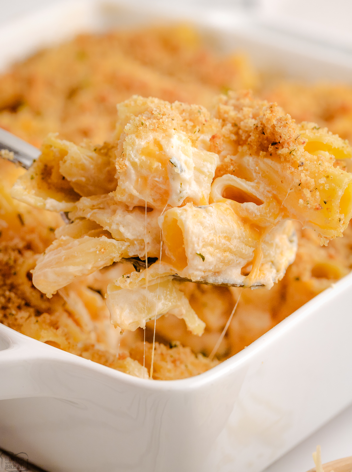 serving up baked rigatoni from a white baking dish