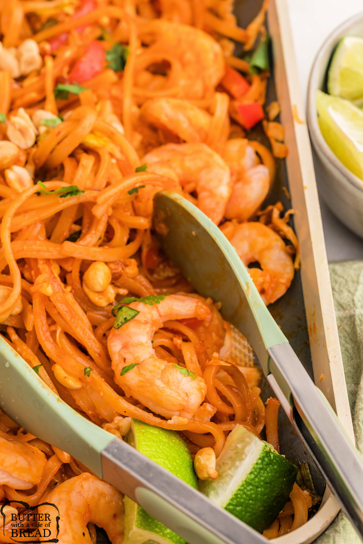 Baked shrimp pad thai with lime wedges for serving.