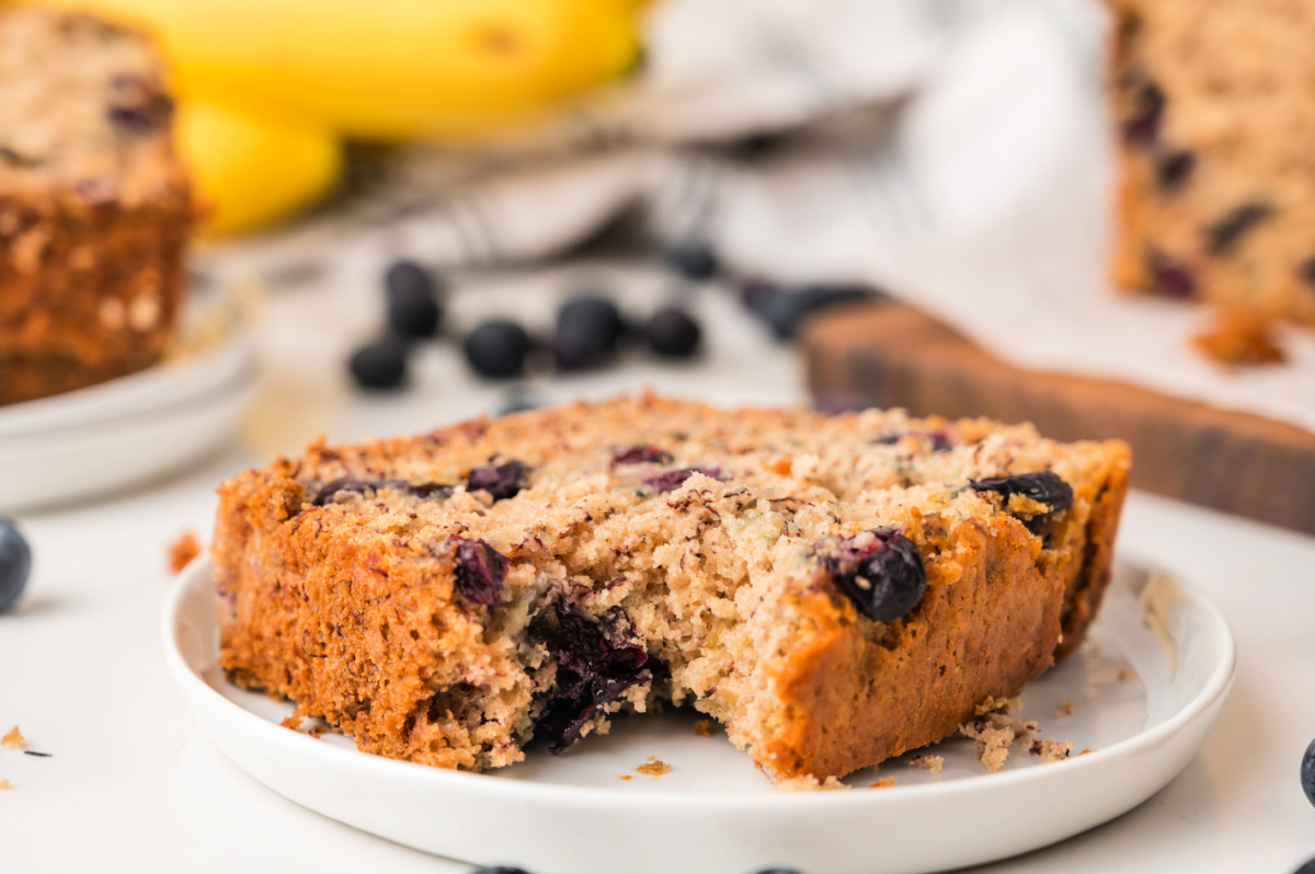 A close-up of moist blueberry banana bread with ripe bananas and fresh blueberries.